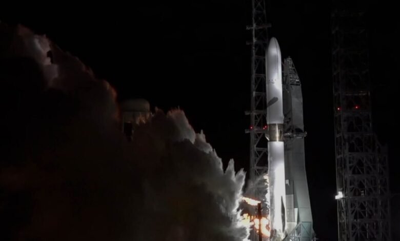 A rocket launching at night, enveloped in thick white smoke and illuminated by bright flames.