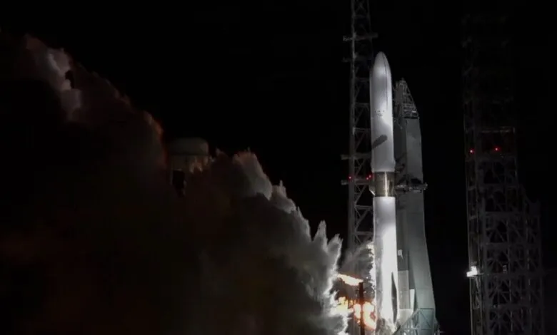 A rocket launching at night, enveloped in thick white smoke and illuminated by bright flames.