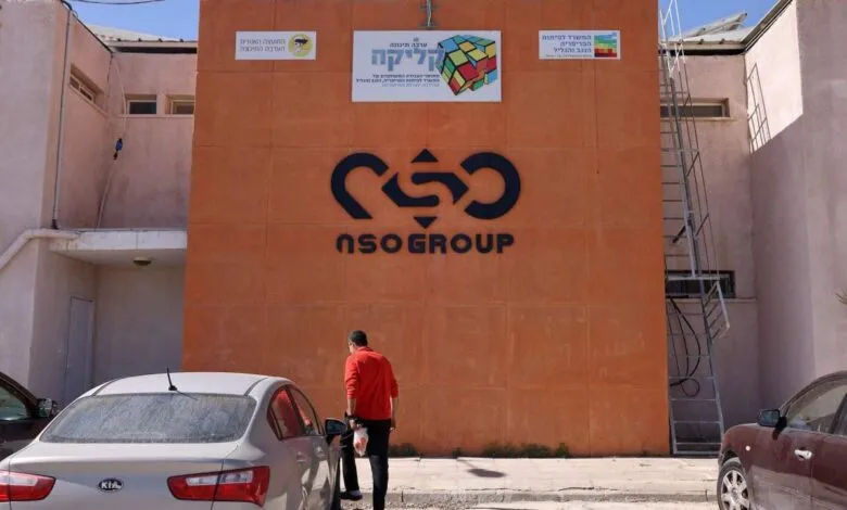 NSO Group logo on an orange building facade with a man walking towards a car.