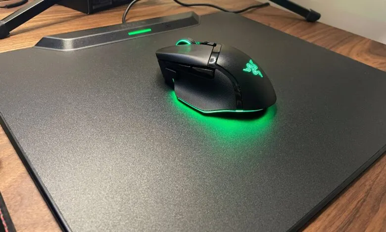 A black Razer gaming mouse with green LED lighting sits on a black mousepad.
