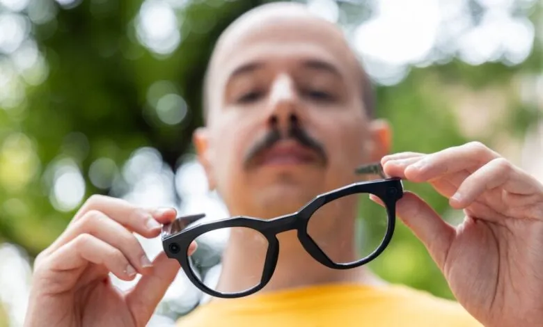 Man holding black smart glasses with camera lenses