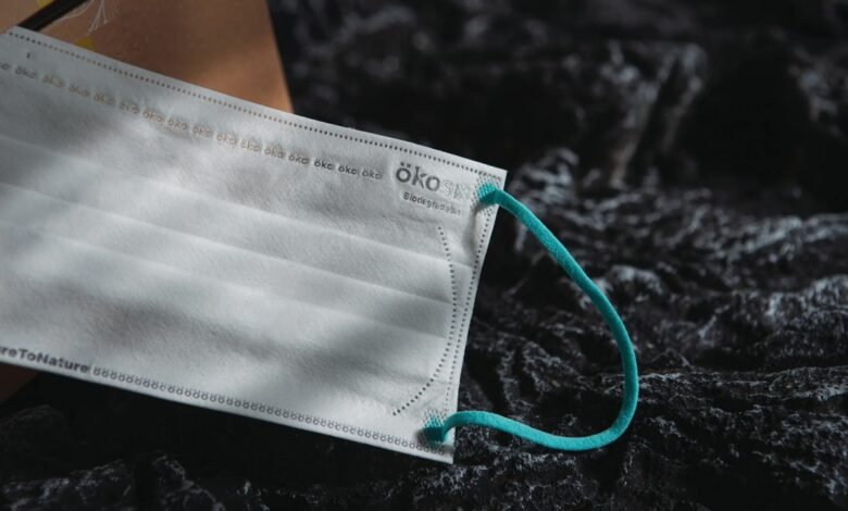 Close-up of a white biodegradable face mask with a teal ear loop.