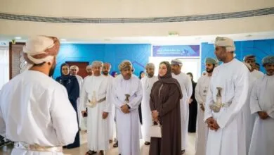 Group of Omani men and women in traditional attire gathered indoors.