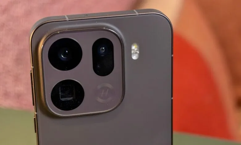 Close-up of a dark gray smartphone's rear camera module with three lenses and a flash.