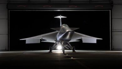 Futuristic aircraft with delta wings parked inside a hangar at night.