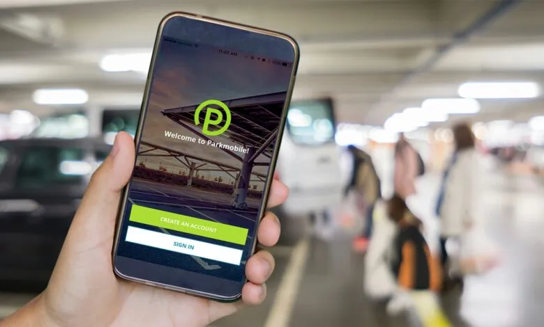Hand holding a smartphone displaying the Parkmobile app login screen in a parking garage.