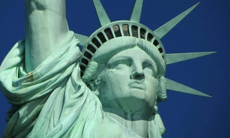 Close-up of the Statue of Liberty's face and crown against a clear blue sky.