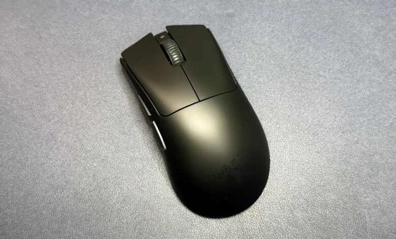 A black Razer gaming mouse with a textured scroll wheel rests on a grey textured surface.