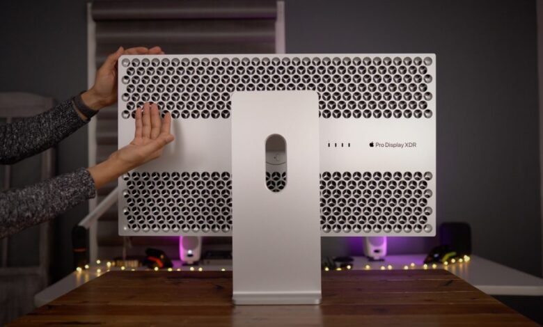 Hands adjusting the back of an Apple Pro Display XDR monitor.