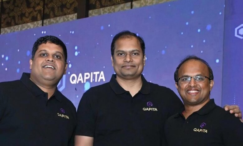 Three men in black Qapita branded polo shirts smile for a photo in front of a blue backdrop.