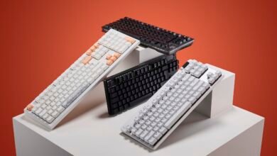 Four mechanical keyboards arranged on white pedestals against an orange background.