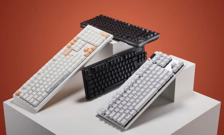 Four mechanical keyboards arranged on white pedestals against an orange background.