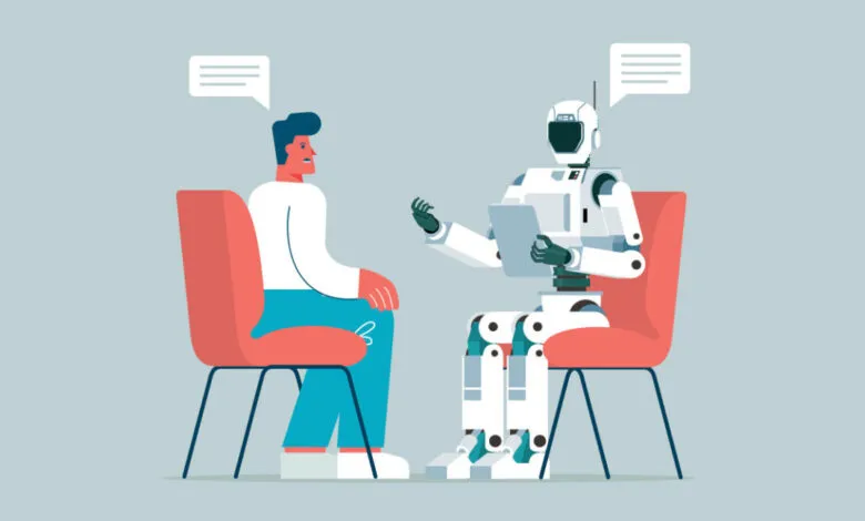 A man in a white shirt and blue pants sits in a red chair, talking to a white robot in another red chair.