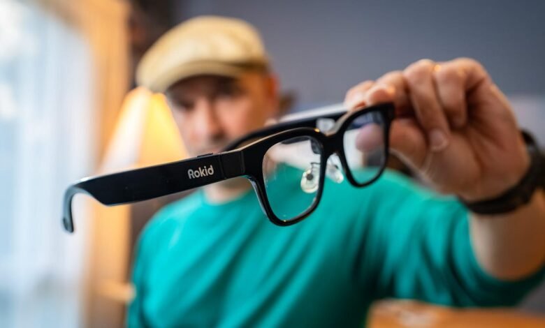 Man holding Rokid augmented reality glasses with the logo visible.
