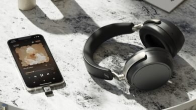 Black Sennheiser headphones and an iPhone playing music on a textured surface.