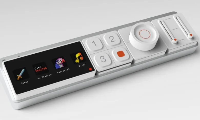 Close-up of a white and silver digital audio controller with a screen displaying pixelated icons.