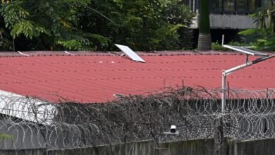 Starlink satellite dish on a red metal roof behind barbed wire.