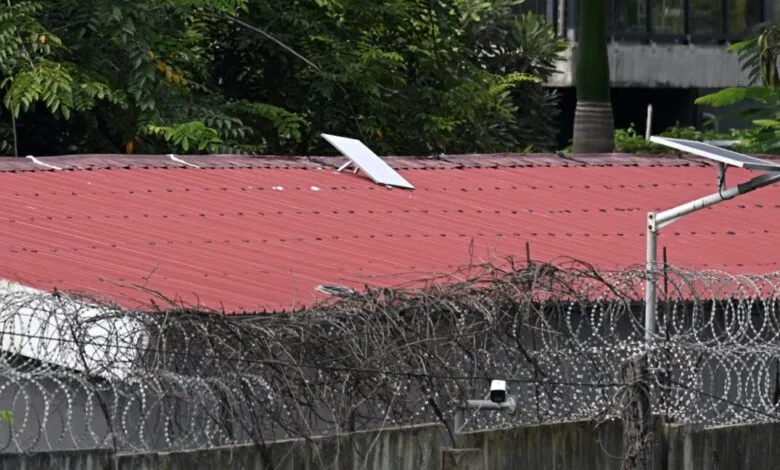 Starlink satellite dish on a red metal roof behind barbed wire.