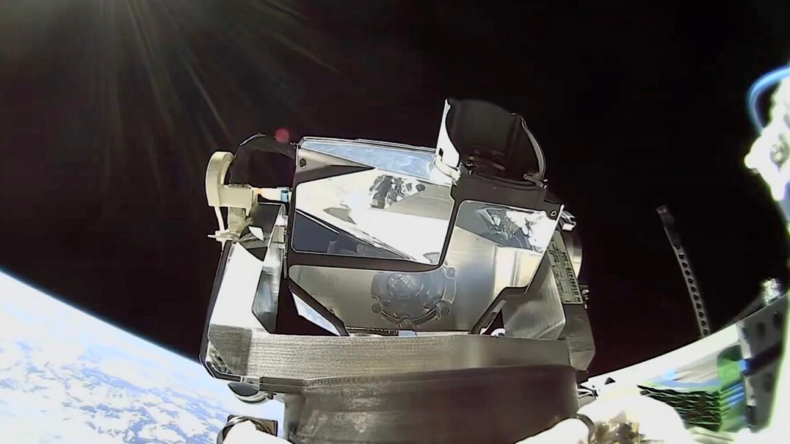 Spacecraft module with reflective surfaces against the backdrop of Earth and space.