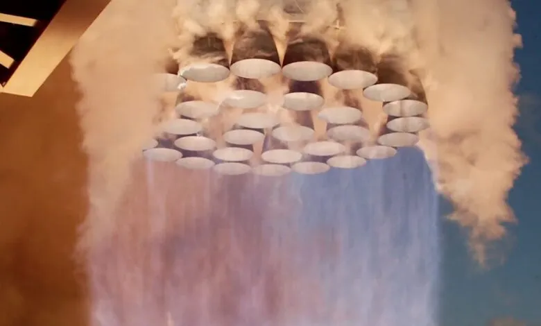 Close-up of multiple rocket engine nozzles expelling thick orange and blue smoke during launch.