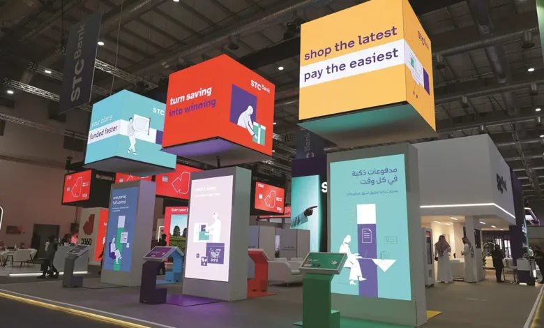 STC Bank exhibition booth with floating cube displays and interactive screens.