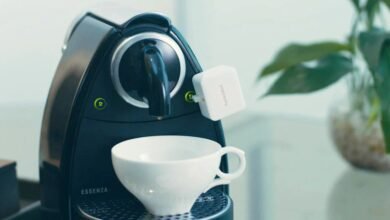 SwitchBot device attached to a black Nespresso Essenza coffee machine.