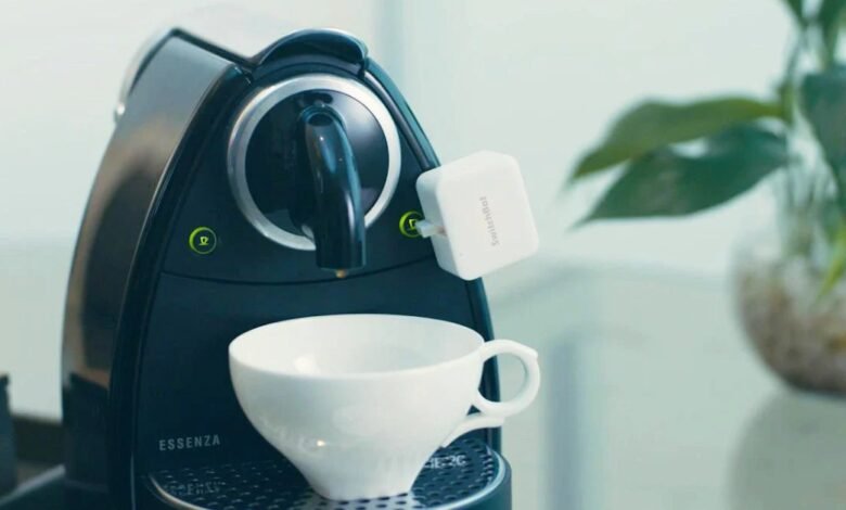 SwitchBot device attached to a black Nespresso Essenza coffee machine.