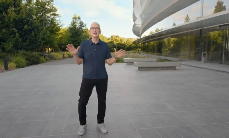 Tim Cook gestures with open hands in front of the Apple Park visitor center.