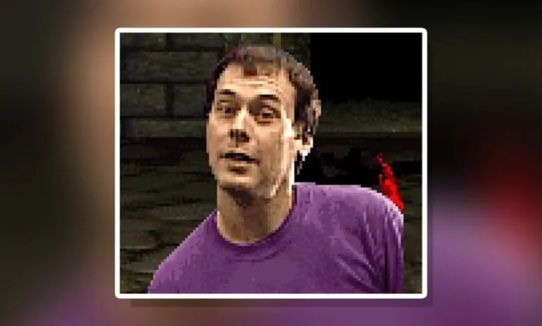 Pixelated close-up of a man with short brown hair wearing a purple t-shirt.