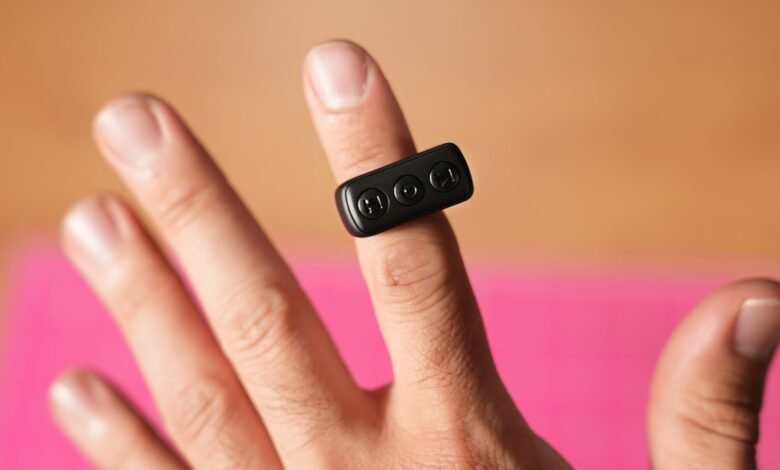 Close-up of a finger wearing a small black ring with three circular buttons.