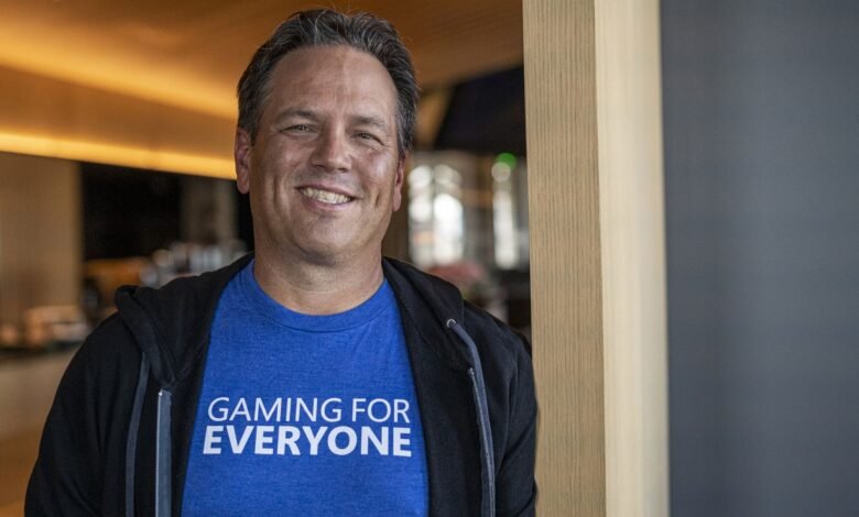Phil Spencer smiles, wearing a blue t-shirt that says "GAMING FOR EVERYONE".