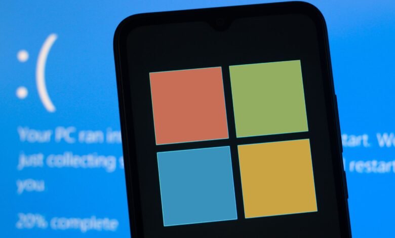 Smartphone displaying the Windows logo next to a blue screen error with a sad face.