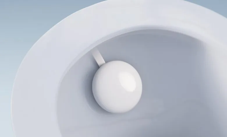 Close-up of a white spherical sensor with a white strap inside a white toilet bowl.