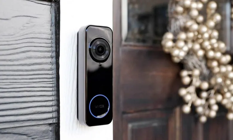 Wyze video doorbell mounted next to a wooden door with a festive wreath