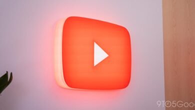 Illuminated YouTube logo with a white play button on a wall.