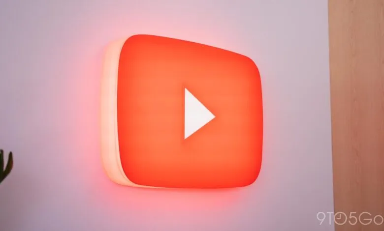 Illuminated YouTube logo with a white play button on a wall.