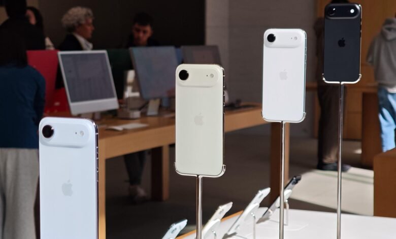 Several iPhones displayed vertically on stands in a retail store.