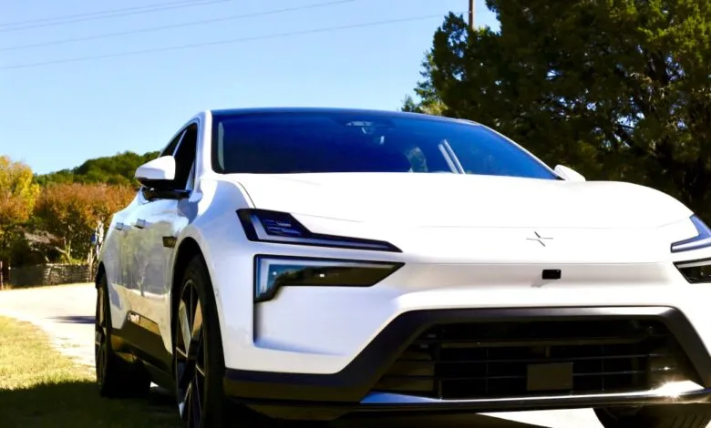 Front view of a white Polestar 4 electric car parked on a grassy roadside.