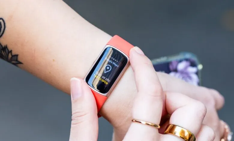 Close-up of a person's wrist wearing a coral Fitbit Charge 6 with Google Maps open.