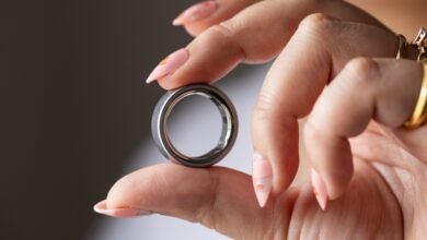 Hand holding a silver Oura Ring, showcasing its design and technology.