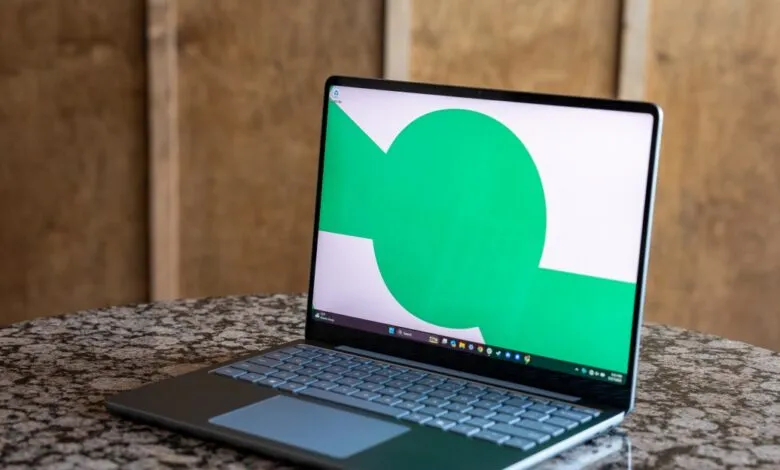 Microsoft Surface Laptop with green and white screen on marble table.