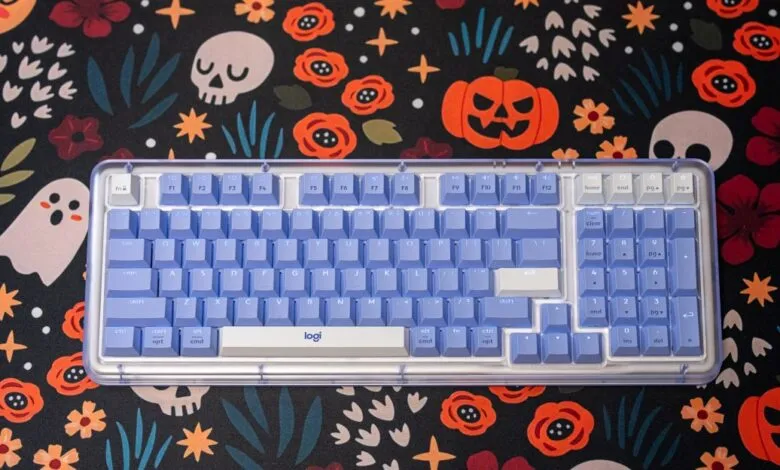 A light purple mechanical keyboard with a clear case rests on a Halloween-themed desk mat.