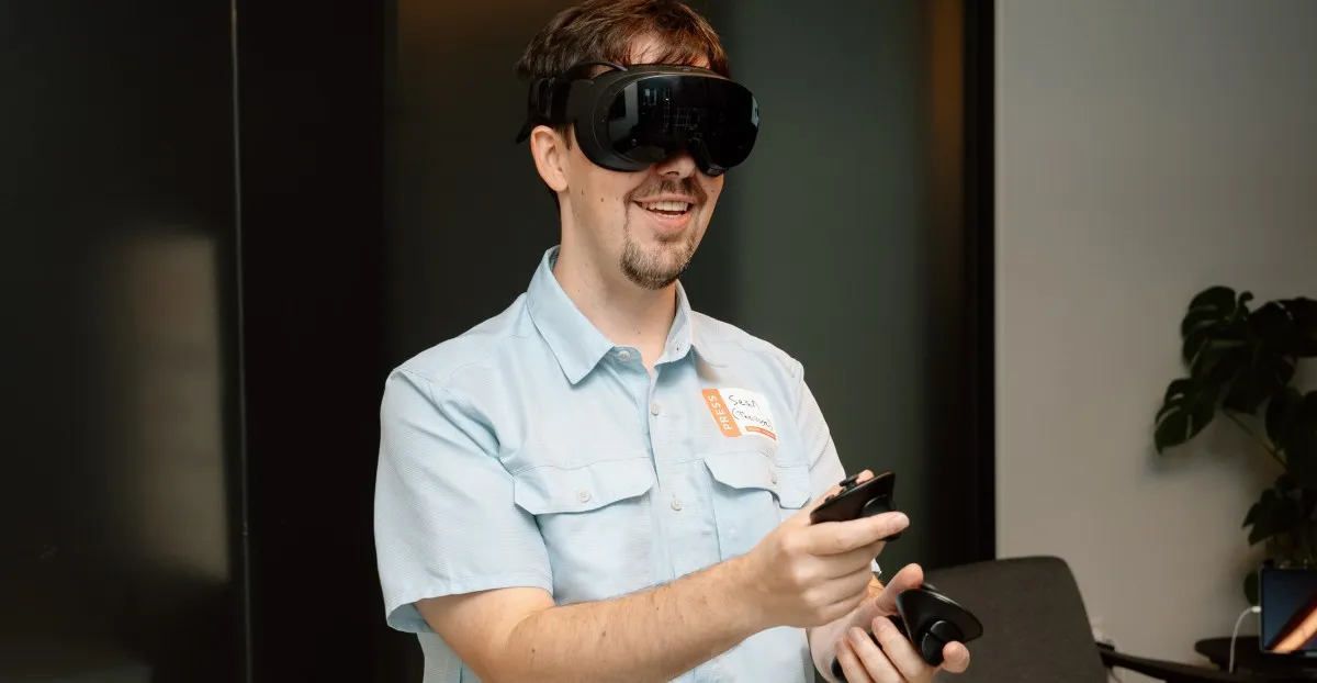 Man wearing VR headset and holding controllers, smiling.