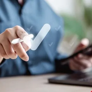 Close-up of a person's hand using a stylus to interact with a digital checkmark.