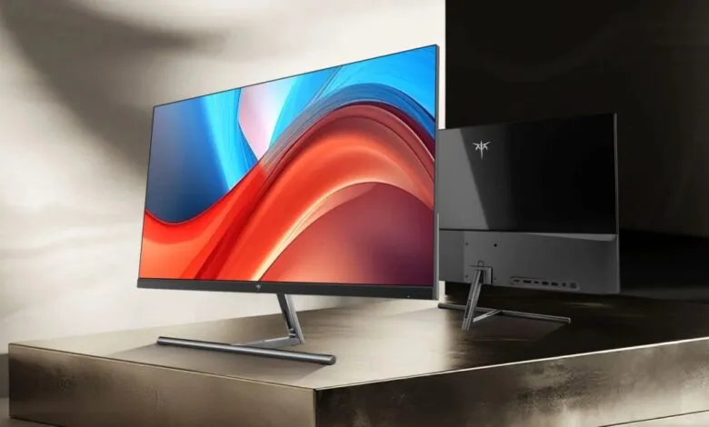 Two sleek monitors on a reflective surface, one displaying vibrant colors.