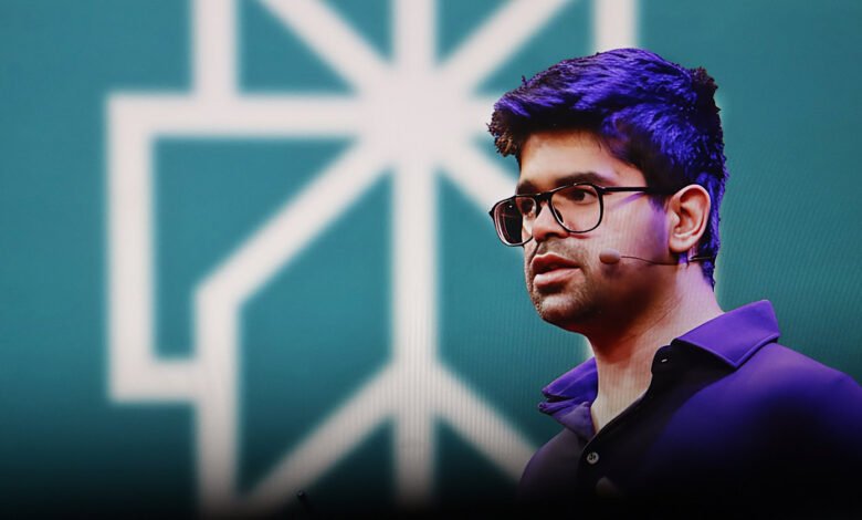 Aravind Srinivas, CEO of Perplexity AI, speaking on stage with a teal background and a white geometric logo.