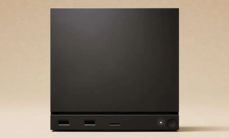 Sleek black gaming console with USB ports and power button on a light wood surface.