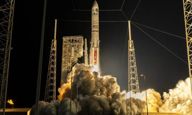 Rocket launching at night, surrounded by smoke and support structures.