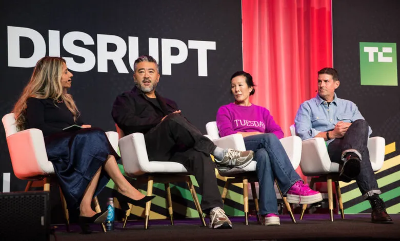 Four people sitting on white chairs on a stage, with the word DISRUPT behind them.