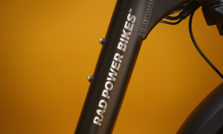 Close-up of a black Rad Power Bikes frame with silver lettering against a yellow background.